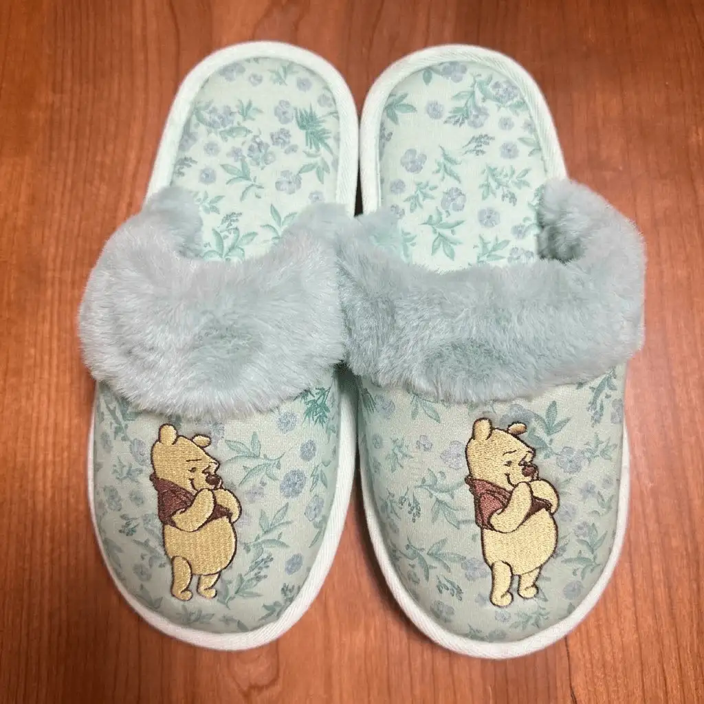 Custom plush slippers featuring high-density computerized embroidery of a bear logo on a floral fabric vamp.