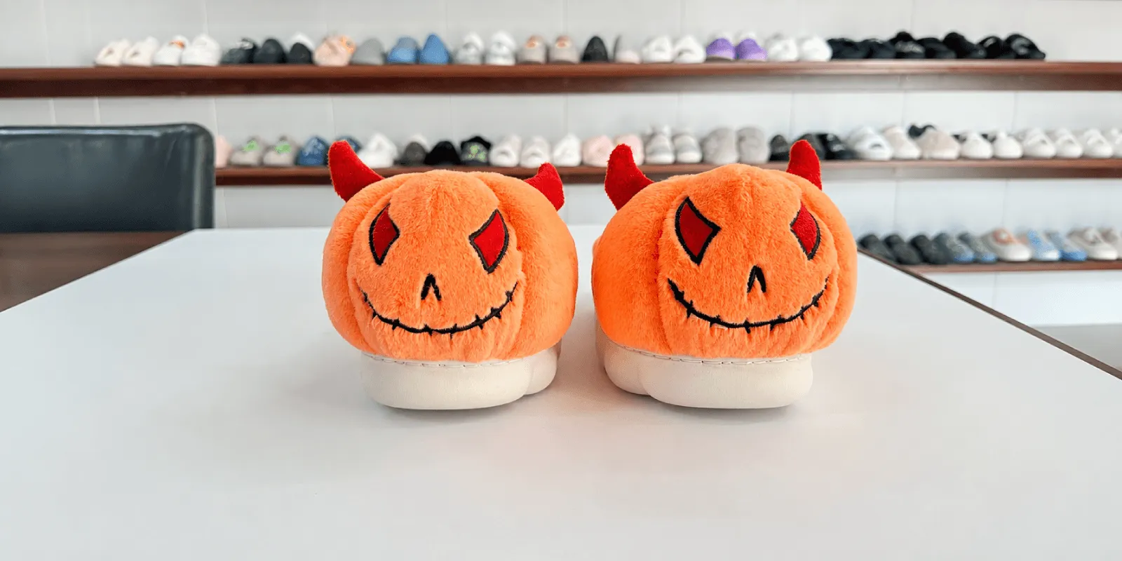 Two orange custom plush slipper samples with 3D horn details and embroidered faces